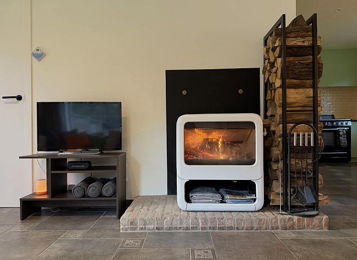 Cozy living room in Lierelodge vacation home, Oud-Turnhout, with wood stove and view of the green garden from the comfortable sitting area.