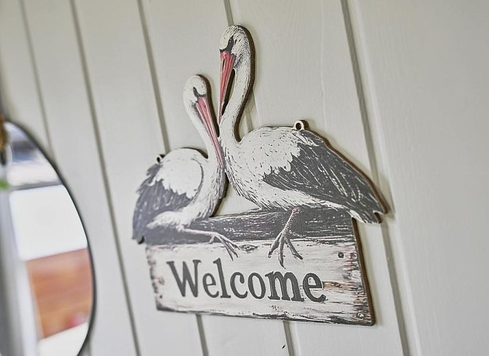 Gezellige woonkamer van chalet Ooievaarsnest in Geel, Antwerpen, Belgie, met comfortabele bank en decoratieve wereldkaart aan de muur.