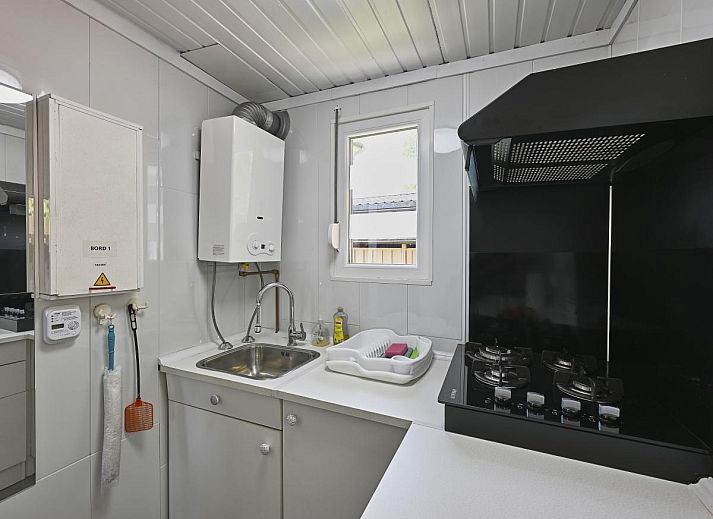 Gezellige woonkamer van chalet Ooievaarsnest in Geel, Antwerpen, Belgie, met comfortabele bank en decoratieve wereldkaart aan de muur.