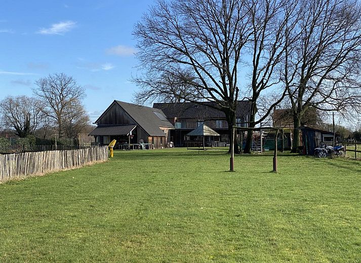 De Lieshoeve vakantiehuis in Arendonk, Antwerpen, Belgie met een uitgestrekt groen veld en bomen in een rustige landelijke omgeving.