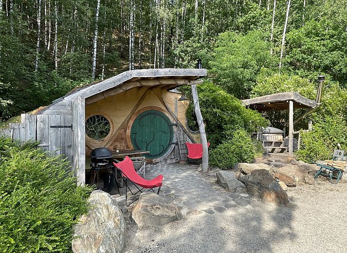 Hobbit House 1 in Neeroeteren, Limburg, Belgie, een uniek vakantiehuis met een rustieke veranda omringd door weelderige natuur.