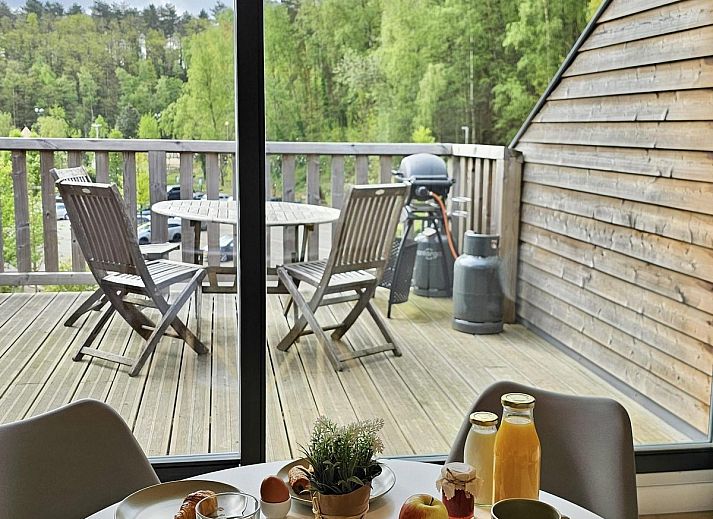 Fruehstueck auf der Terrasse des Plus Studio Ferienhauses in Neeroeteren, Limburg mit Blick auf die gruene Umgebung.