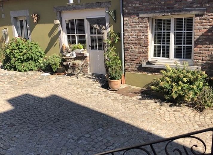 Charmante binnenplaats van vakantiehuis FreLune in Tongeren, Limburg, Belgie met rustieke stenen en groene accenten.