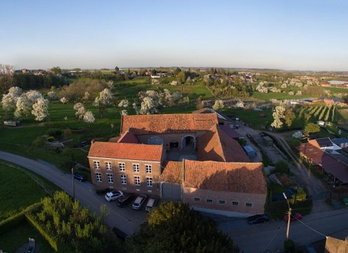 Luchtfoto van Servaeshoeve - Gerstebaard, een vakantiehuis in het pittoreske Borgloon, Limburg, omgeven door bloeiende boomgaarden en groene velden.