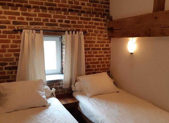 Gezellige slaapkamer in Servaeshoeve - Gerstebaard, vakantiehuis in Borgloon, Limburg, Belgie met rustieke bakstenen muur en houten balken.