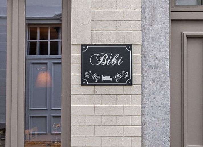 Gezellige woonkamer van vakantiehuis Bibi Tongeren in Limburg, Belgie met rustieke stenen muur en comfortabele zitruimte.