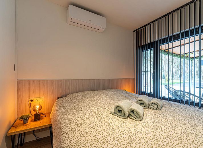 Knusse slaapkamer in Aperol Spritz vakantiehuis, Zutendaal, Limburg met sfeervolle verlichting.