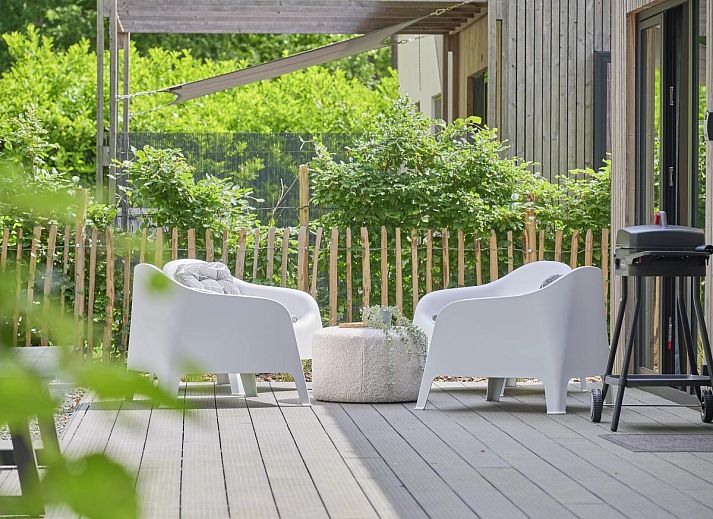 Gezellige woonkamer in De Eekhoorn vakantiehuis, Zutendaal, met comfortabele bank en uitzicht op de tuin.