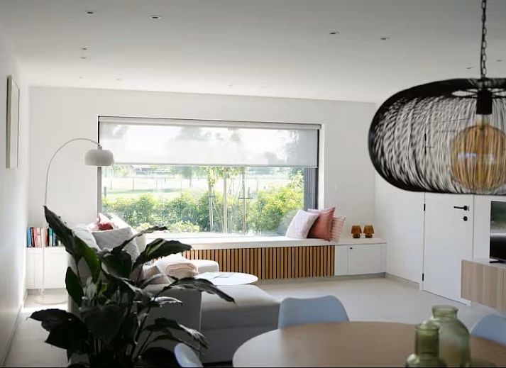 Lichte woonkamer in Ten Huyze Bucholt, een vakantiehuis met tuinsauna in Bocholt, Limburg, Belgie, met uitzicht op de groene omgeving.