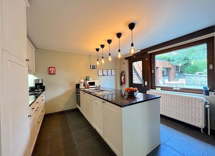 Moderne Kueche des Ferienhauses Aux Hirondelles in Malmedy, Ardennen, mit Bar und Beleuchtung.