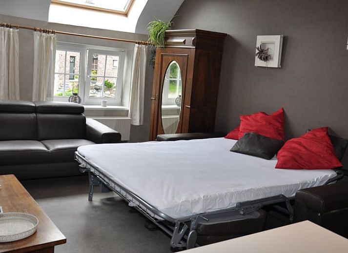 Cozy living room in Holiday Home in Hombourg, Ardennes, with comfortable sitting area and open kitchen, perfect for relaxation in Belgium.