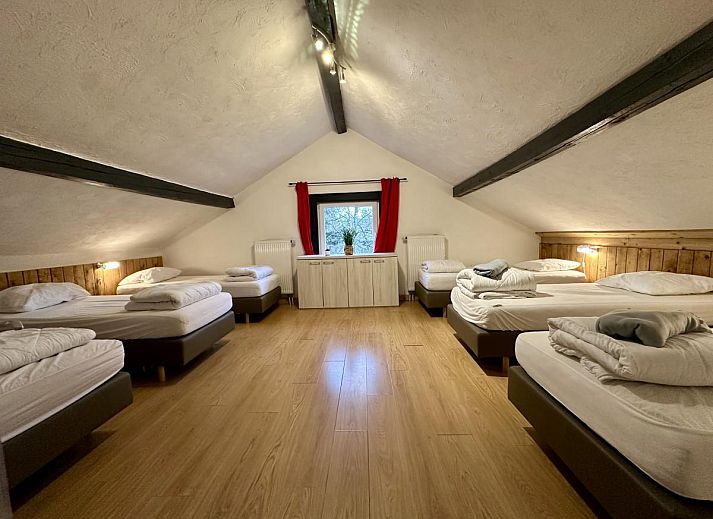 Ruime eetkamer van vakantiehuis Annexe in Sourbrodt, Ardennen, Belgie met lange houten tafel en moderne keuken in de achtergrond.