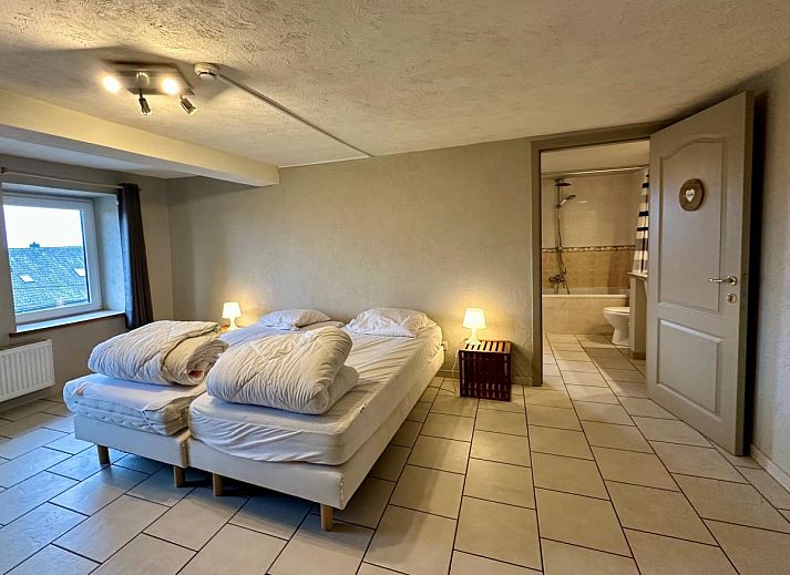 Ruime eetkamer van vakantiehuis Annexe in Sourbrodt, Ardennen, Belgie met lange houten tafel en moderne keuken in de achtergrond.