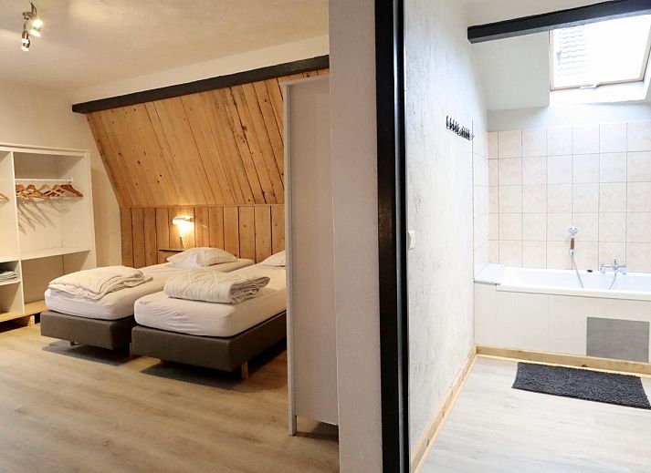 Ruime eetkamer van vakantiehuis Annexe in Sourbrodt, Ardennen, Belgie met lange houten tafel en moderne keuken in de achtergrond.