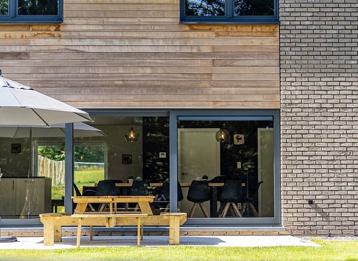 Ruime eetkamer in Vakantiehuisje in Sourbrodt, Ardennen met uitzicht op groene tuin, ideaal voor een ontspannende vakantie in Belgie.