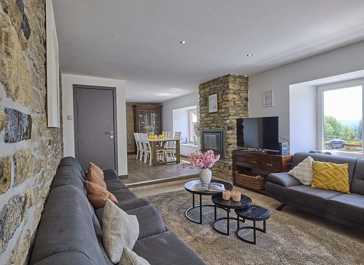 Gemuetliches Wohnzimmer im Ferienhaus "La Ferme" in Lierneux, Ardennen, mit bequemen Sofas und rustikalen Steinwaenden in Belgien.
