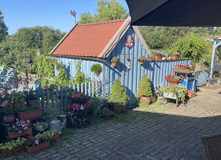 Gezellige veranda van De Eifelhoeve vakantiehuis in Herresbach, Ardennen, Belgie, met blauwe kussens en decoratieve elementen.