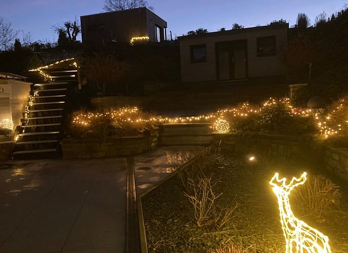 Gemuetliche Sitzecke im Ferienhaus in Spa, Ardennen, Belgien, mit bequemen Stuehlen und Blick auf den Garten.