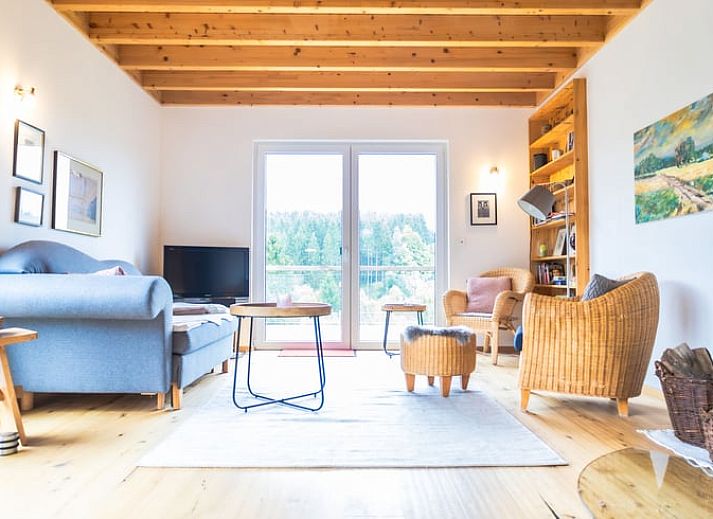 Das Ferienhaus in Kuechelscheid in den Ardennen, Belgien, bietet einen charmanten Aussenbereich mit einem gruenen Garten und einer rustikalen Holzfassade.