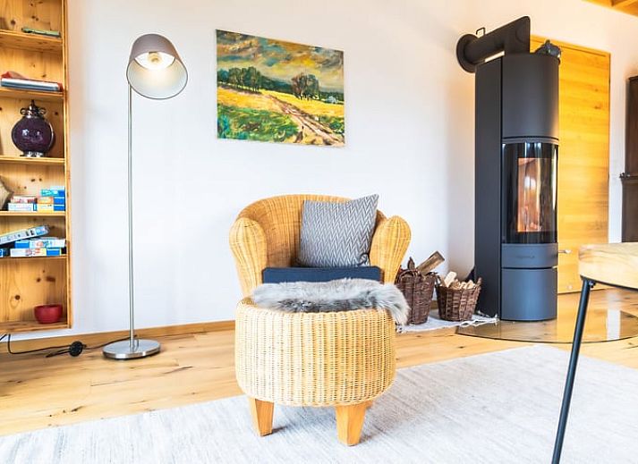 Das Ferienhaus in Kuechelscheid in den Ardennen, Belgien, bietet einen charmanten Aussenbereich mit einem gruenen Garten und einer rustikalen Holzfassade.