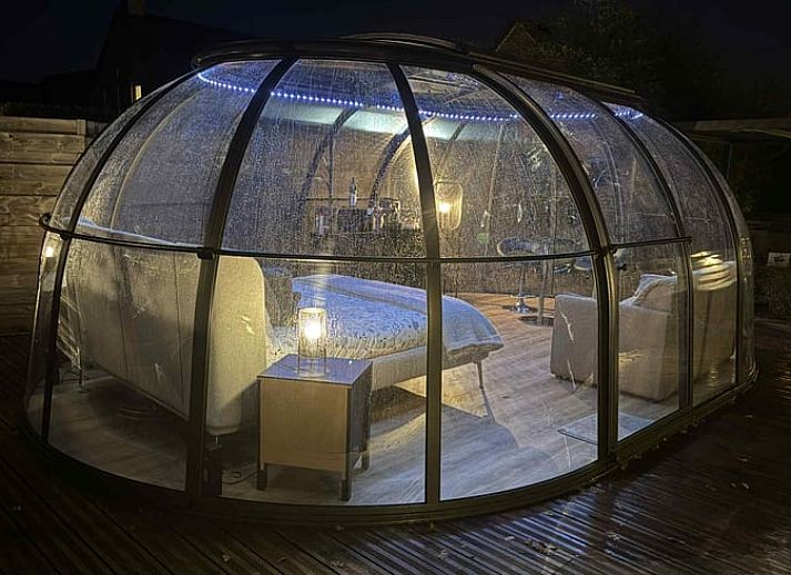 Ontspan in de jacuzzi bij Vakantiehuisje in Havinnes, Belgie, met sfeervolle verlichting en uitzicht op de natuur.