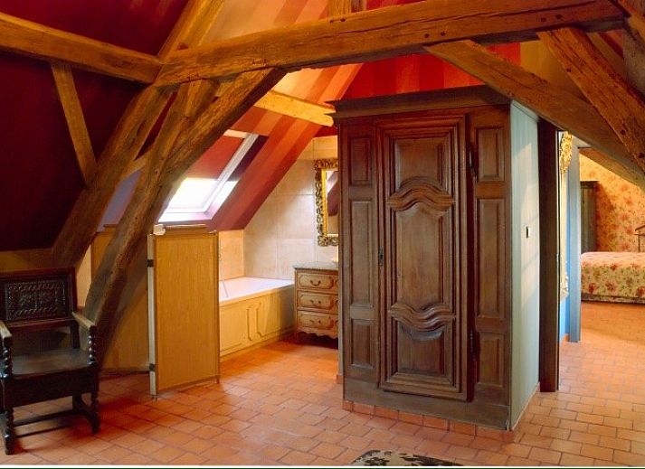 Gemuetlicher Speisesaal im Les Confidences de Messire Sanglier, Beauraing, mit antikem Tisch und stimmungsvoller Beleuchtung.