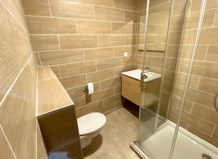 Terrasse von Le Moulin De Romedenne in Philippeville, Ferienhaus in den Ardennen mit gruenen Sonnenschirmen und Holztischen.