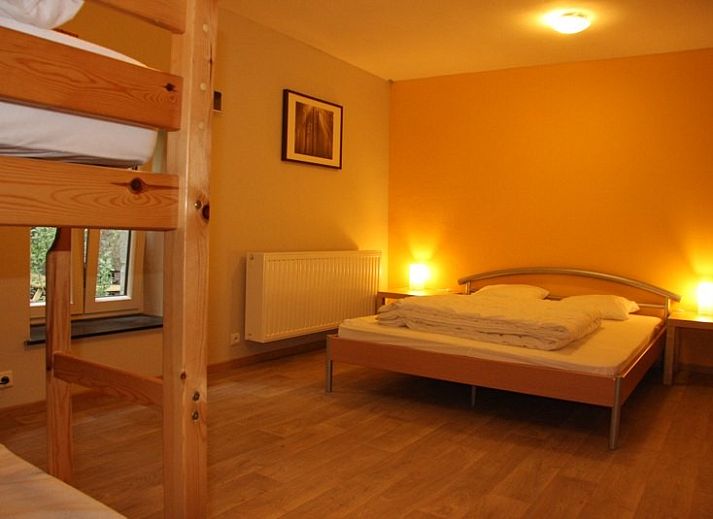 Terrasse von Le Moulin De Romedenne in Philippeville, Ferienhaus in den Ardennen mit gruenen Sonnenschirmen und Holztischen.