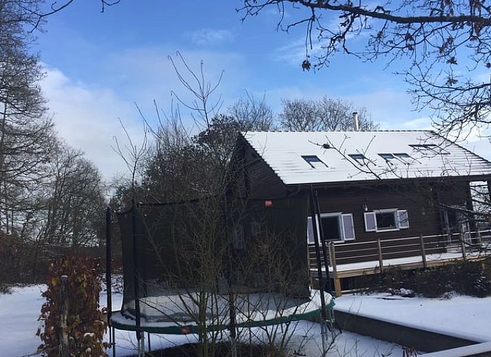 Geniessen Sie die natuerliche Umgebung im Ferienhaus in Heure, Ardennen, Belgien, mit einem Trampolin zwischen den Baeumen fuer Spass im Freien.