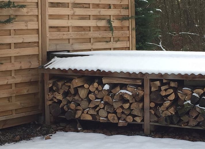Gemuetlicher Innenbereich des Ferienhauses in Heure, Ardennen, Belgien mit grossem Esstisch und Blick auf die Natur.