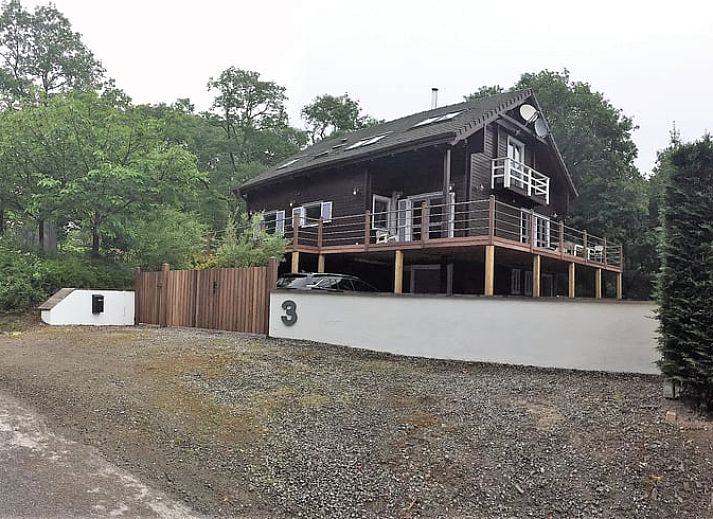 Gemuetlicher Innenbereich des Ferienhauses in Heure, Ardennen, Belgien mit grossem Esstisch und Blick auf die Natur.
