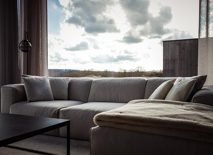 Modernes Wohnzimmer im Ferienhaus La Ruree, Heure, Ardennen, Belgien, mit stilvoller Einrichtung und grossen Fenstern fuer natuerliches Licht.