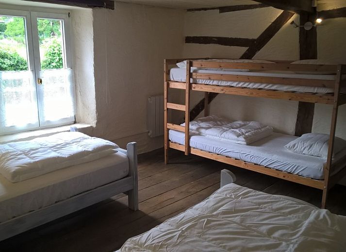 Gezellige woonkamer van vakantiehuis Le Colombage in Honnay, Ardennen, met houtkachel en tafelvoetbal voor een ontspannen verblijf.
