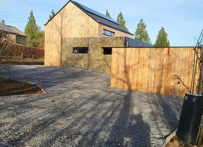 Cottage in Grandmenil, cottage in the Ardennes, Belgium with modern wooden facade and spacious driveway surrounded by nature.