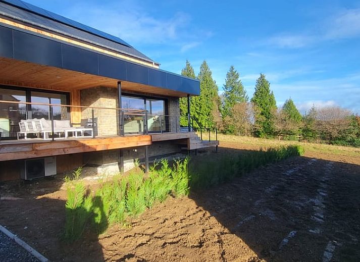 Cottage in Grandmenil, cottage in the Ardennes, Belgium with modern wooden facade and spacious driveway surrounded by nature.