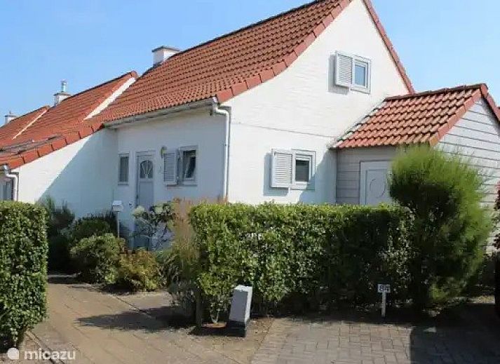 Charmant vakantiehuis Seaside Village, huisje 77, in Vosseslag bij De Haan aan de Belgische kust, met rode daken en groene heggen.