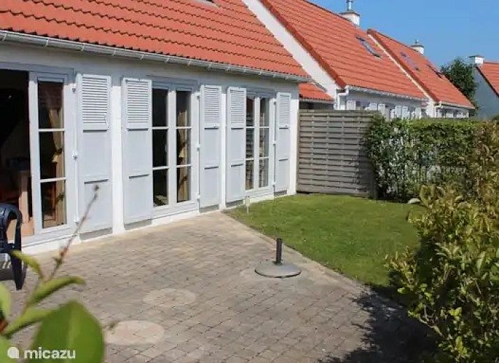 Charmant vakantiehuis Seaside Village, huisje 77, in Vosseslag bij De Haan aan de Belgische kust, met rode daken en groene heggen.