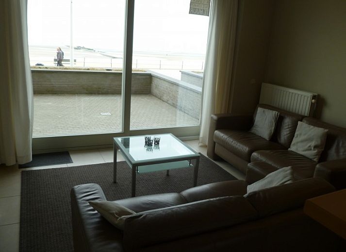Gezellige woonkamer in Symfonie - Residentie appartement, Koksijde, met comfortabele banken en uitzicht op het terras.
