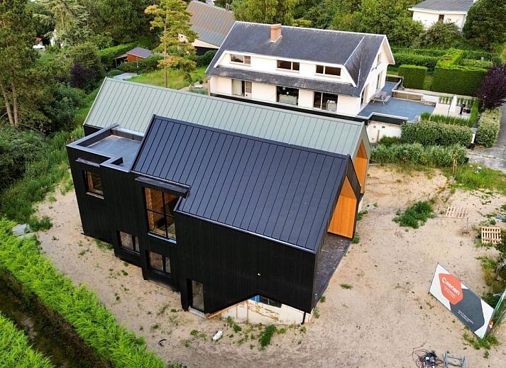 Moderne vrijstaande woning in Koksijde aan de Belgische kust, vakantiehuis met glazen gevel en uitzicht op groene omgeving.