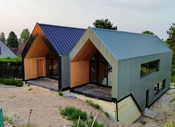 Moderne vrijstaande woning in Koksijde aan de Belgische kust, vakantiehuis met glazen gevel en uitzicht op groene omgeving.