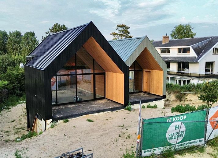 Moderne vrijstaande woning in Koksijde aan de Belgische kust, vakantiehuis met glazen gevel en uitzicht op groene omgeving.