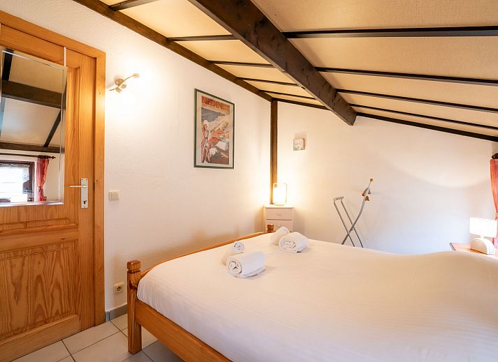 Sfeervolle slaapkamer in Vakantiehuis Zeewind II in Bredene, Belgische kust, met houten balken en zacht beddengoed voor een rustgevend verblijf.