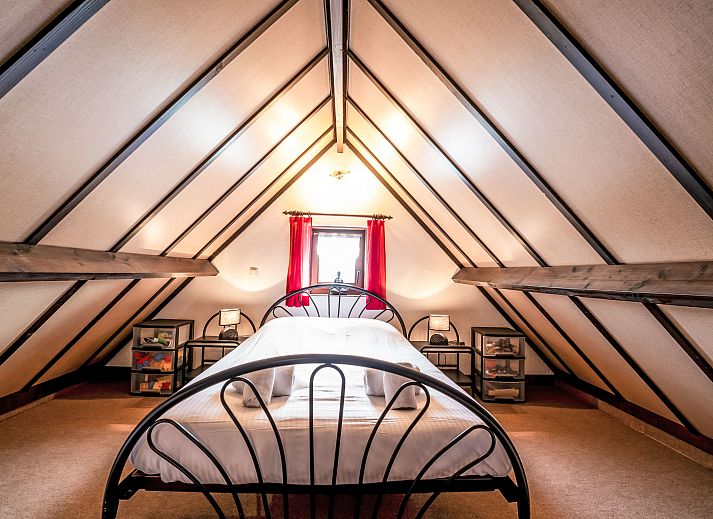 Sfeervolle slaapkamer in Vakantiehuis Zeewind II in Bredene, Belgische kust, met houten balken en zacht beddengoed voor een rustgevend verblijf.