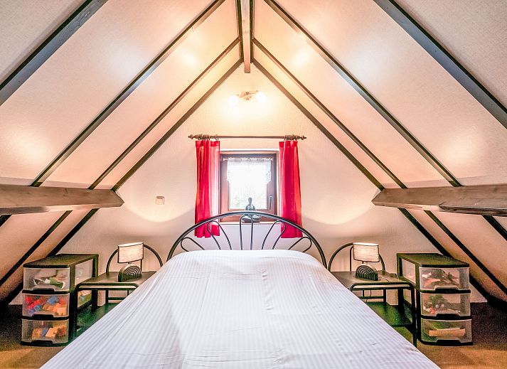 Sfeervolle slaapkamer in Vakantiehuis Zeewind II in Bredene, Belgische kust, met houten balken en zacht beddengoed voor een rustgevend verblijf.
