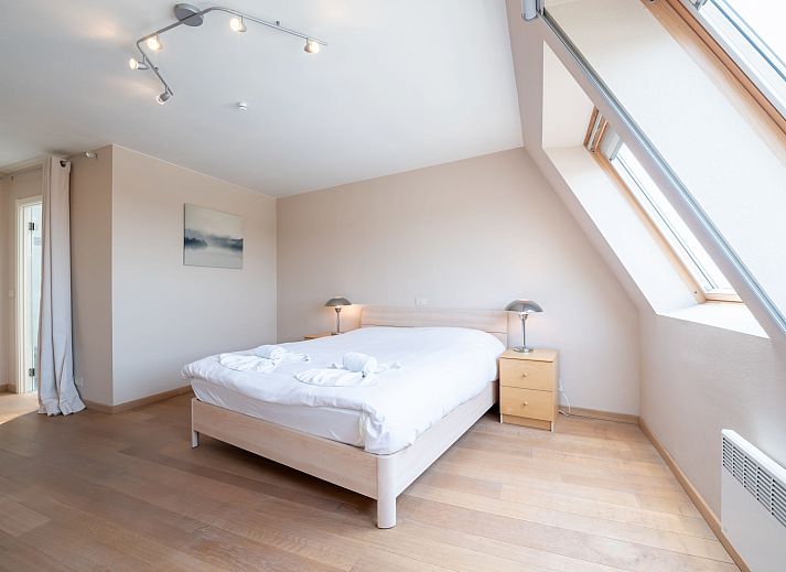 Dining room of Apartment Queen Mary in Bredene, Belgian coast. Cozy space with wooden table and art on the wall for a relaxing stay.