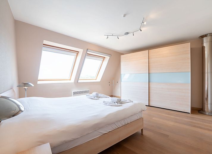 Dining room of Apartment Queen Mary in Bredene, Belgian coast. Cozy space with wooden table and art on the wall for a relaxing stay.