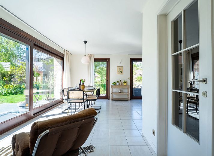 Gemuetliches Wohnzimmer des Ferienhauses Villa Zeebries in Bredene, belgische Kueste, mit Kamin und Gartenblick.