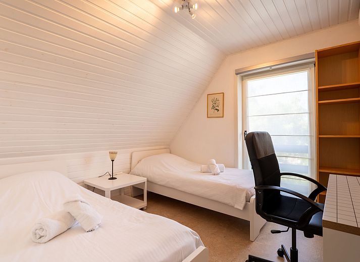 Gemuetliches Wohnzimmer des Ferienhauses Villa Zeebries in Bredene, belgische Kueste, mit Kamin und Gartenblick.