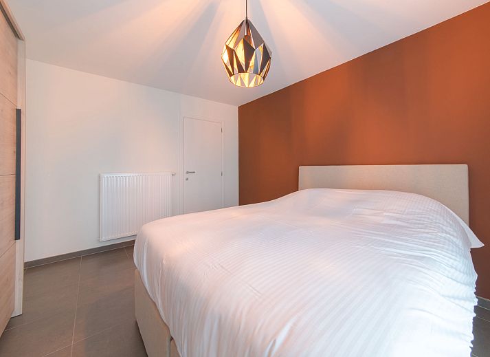 Cozy living room of Apartment Ocean in Bredene, Belgian coast, overlooking nature through large windows.