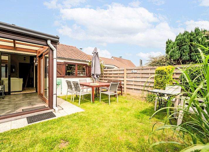 Helle Veranda des Ferienhauses Reynaertpark in Bredene, belgische Kueste, mit Blick auf den Garten und bequemen Sitzgelegenheiten.